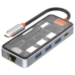 Det här är en bild av en USB-C-hubb med flera portar och ett synligt internt kretskort. Hubben har flera USB-A-portar, en Ethernet-port och ytterligare en USB-C-port. Höljet är transparent på ovansidan, vilket gör att de interna komponenterna är synliga. USB-C-kabeln som är ansluten till hubben har en metallkontakt med en orange accent nära kontakten. Denna hubb verkar vara ett multifunktionellt tillbehör för enheter som bärbara datorer eller surfplattor, och erbjuder ytterligare anslutningsmöjligheter. Ethernet-porten är placerad i ena änden av enheten och USB-A-portarna är placerade längs sidan.