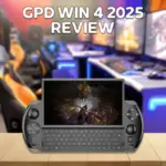 A thumbnail image for a video review of the GPD WIN 4 2025 handheld gaming console. The black, horizontally oriented console is shown resting on a wooden surface, with its sliding screen lifted to reveal the full QWERTY keyboard and game controls. The screen displays a dark, fantasy action game with a character battling a large monster. Large white text overlaid at the top of the image reads "GPD WIN 4 2025 REVIEW." The background is a blurred image of a gaming setup with an orange and black gaming chair and illuminated monitors.