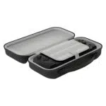Úhlový, otevřený pohled na černý kufřík. Vnitřek je světle šedý a černá konzola GPD WIN 5 je ve spodní polovině upevněna bílým páskem. Obrazovku zakrývá šedá přepážka s bílými pruhy a horní polovina kufříku je prázdná. Kufřík je vybaven integrovanou rukojetí pro přenášení.