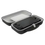 Úhlový, otevřený pohled na černý kufřík. Vnitřek je světle šedý a černá konzola GPD WIN 5 je ve spodní polovině upevněna bílým páskem. Přes zařízení je umístěn pevný bílý ochranný kryt/rozdělovač obrazovky a horní polovina pouzdra je prázdná. Kufřík je vybaven integrovanou rukojetí pro přenášení.