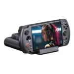 تظهر وحدة تحكم GPD WIN 5 المحمولة باليد سوداء اللون مثبتة في قاعدة الشحن/البيانات السوداء المطابقة لها، مائلة إلى الأمام على خلفية بيضاء. تعرض شاشة وحدة التحكم صورة عن قرب لشخصية أنثوية بشعر وردي اللون مع تحسينات إلكترونية. تظهر أزرار التحكم في الجهاز ومؤشرات LED الأربعة في قاعدة الإرساء بوضوح.