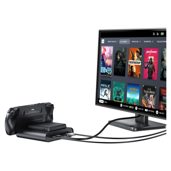 Een zwarte GPD WIN 5 handheld console wordt getoond in het dock en is via kabels verbonden met een monitor. De monitor toont de Steam OS-stijl interface met een raster van speltitels zoals Dead Cells, Deathloop, Portal 2 en Stardew Valley, wat de mogelijkheid van het apparaat illustreert om een desktop spelervaring aan te sturen. 