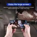 Dzīvesstila attēls ar nosaukumu "Izbaudiet lielo ekrānu", kurā attēlots cilvēks, kas, spēlējot spraiga sižeta videospēli, horizontāli tur viedtālruni. Tālrunis ir savienots ar USB-C kabeli ar lielu televizoru fonā, kas atspoguļo to pašu spēles grafiku. Tekstā aprakstīts "Reāllaika ekrāna projekcija mobilo spēļu grafikai, vienmērīga, bez aizķeršanās, ar plašāku vizuālo diapazonu".