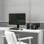 Desk setup with a widescreen monitor displaying code and terminal windows, a compact PC and external GPU enclosure on the right, white chair and blinds in the background