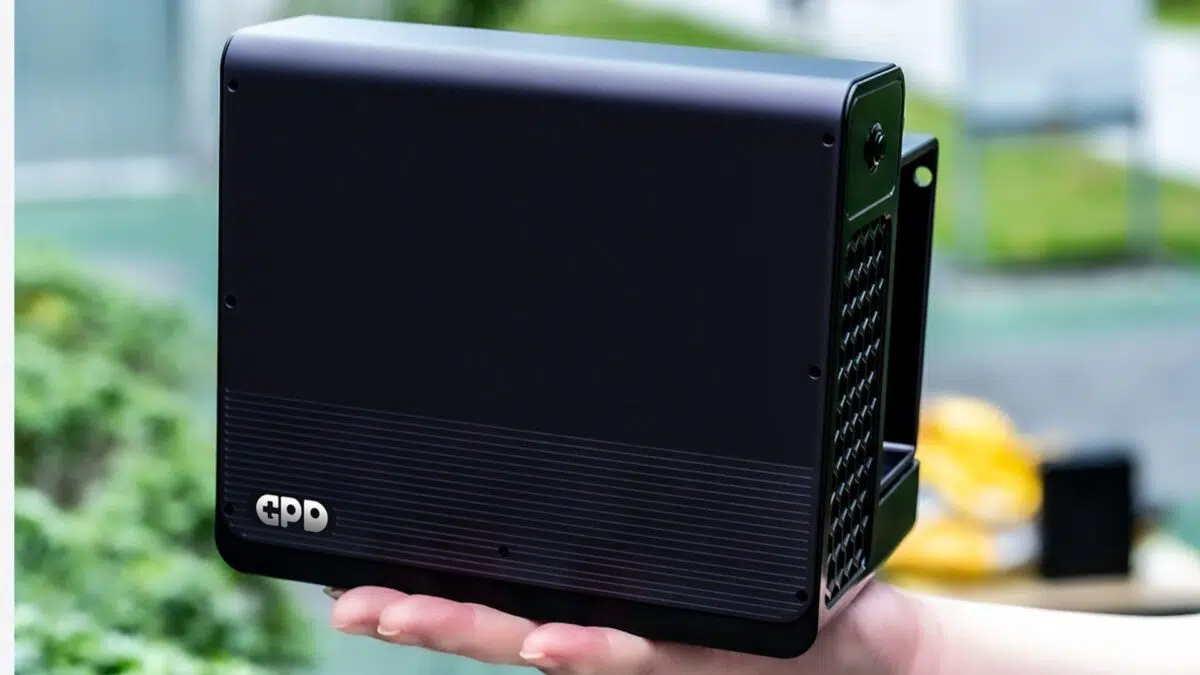 Small black handheld mini PC with cooling vents being held outdoors, showing the GPD logo on the bottom corner.