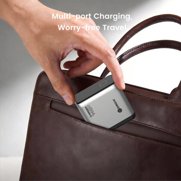 Close-up of a hand placing a silver multi-port charger into the side pocket of a brown leather handbag, with the text 'Multi-port Charging, Worry-free Travel' visible in the background.