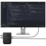 GPD BOX black textured mini PC with round vent, cabled to monitor showing Visual Studio Code